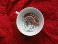 Porcelain teacup with jewelry on red lacy background