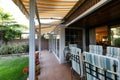 Porch of a detached house with glass latticework, striped awnings and a garden with a lawn and flowers Royalty Free Stock Photo