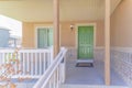 Porch of a house with white railings with lockbox and green front door