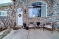 Porch table and chairs against arched window and stone wall at home facade