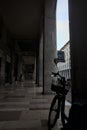 Porchway by the edge of an avenue with shops and people passing by in an italian town at sunset