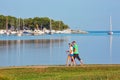 POREC, CROATIA - August 10th, 2019: Mature people enjoying Scandinavian walking along the sea on a nice summer morning