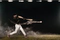 Baseball player with bat taking a swing on grand arena. Ballplayer on dark background in action. Royalty Free Stock Photo