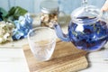 Poring bright blue butterfly pea flower herb tea to glass from a glass teapot Royalty Free Stock Photo