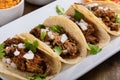 Pork carnitas tacos on corn tortillas with rice and beans