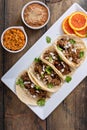 Pork carnitas tacos on corn tortillas with rice and beans