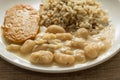 Pork chop, Brown rice and white beans. White dish on wooden table. Detail of food dish, closeup, selective focus.