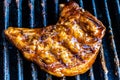 Pork chop grilling on a BBQ covered in BBQ sauce