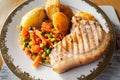 Pork chop with mixed vegetables, roast potatoes and gravy. Home cooked lit by window light Royalty Free Stock Photo