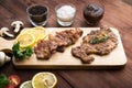 Pork chop steak served on a cutting board with rosemary, pepper and ketch up on wood table