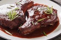 Pork chops on the bone fried and then cooked with red wine, herbs and spices close-up on a plate. Horizontal Royalty Free Stock Photo