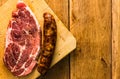 Pork chops with condiments and smoked sausage on a wooden cutting board over wooden table, meat for bbq, top view, copy space, Royalty Free Stock Photo