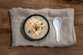 Pork congee or Chinese rice porridge with Minced pork, Egg, Enoki mushroom and Seaweed in bowl with spoon on old wooden table Royalty Free Stock Photo