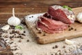 Pork dried meat slices on rustic dark wooden background. Dried pork prosciutto salami ham with herbs. Royalty Free Stock Photo