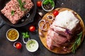 Pork fillet on a cutting board, raw meat, assorted minced pork and beef and various spices on a stone or slate background