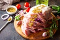 Pork fillet marinated with mustard on a cutting board, raw meat, cherry tomatoes and various spices on a stone or slate background