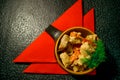 Pork in an interesting dish, baked with vegetables and decorated with dill with red napkins on a black background Royalty Free Stock Photo