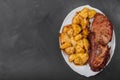 Pork loin steak and potatoes baked with cheese on a white plate, gray background Royalty Free Stock Photo