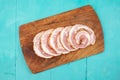 Pork meat roulade sliced on a wood chopping board, flat lay on blue table background, close up Royalty Free Stock Photo