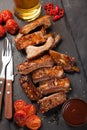 Pork ribs in barbecue sauce and honey baked tomatoes and a glass of beer on a black slate dish. A great snack to beer on a dark st Royalty Free Stock Photo