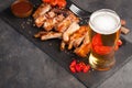 Pork ribs in barbecue sauce and honey baked tomatoes and a glass of beer on a black slate dish. A great snack to beer on a dark st Royalty Free Stock Photo