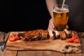 Pork ribs in barbecue sauce and honey baked tomatoes on the old wooden table. Meats and light beer on black background with copy s Royalty Free Stock Photo