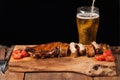 Pork ribs in barbecue sauce and honey baked tomatoes on the old wooden table. Meats and light beer on black background with copy s Royalty Free Stock Photo