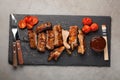 Pork ribs in barbecue sauce and honey roasted tomatoes on a black slate dish. A great snack to beer on a light stone table. Top vi Royalty Free Stock Photo