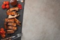 Pork ribs in barbecue sauce and honey roasted tomatoes on a black slate dish. A great snack to beer on a light stone table. Top vi Royalty Free Stock Photo