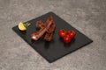 Pork ribs in barbecue sauce and honey roasted tomatoes on a black slate dish. Royalty Free Stock Photo