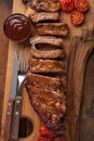 Pork ribs in barbecue sauce and honey roasted tomatoes on a wooden board. A great snack to beer on a rustic wooden table. Top view Royalty Free Stock Photo