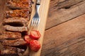 Pork ribs in barbecue sauce and honey roasted tomatoes on a wooden board. A great snack to beer on a rustic wooden table. Top view Royalty Free Stock Photo