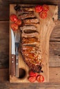 Pork ribs in barbecue sauce and honey roasted tomatoes on a wooden board. A great snack to beer on a rustic wooden table. Top view Royalty Free Stock Photo