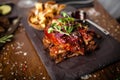 Pork ribs cooked at low temperature. Blackcurrant sauce, parsnip chips with Parmesan cheese. Delicious healthy meat food Royalty Free Stock Photo