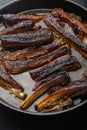 Pork ribs grilled with BBQ sauce and caramelized in honey, in frying cast iron pan, on black stone background Royalty Free Stock Photo