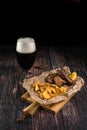 Pork ribs in honey mustard glaze with potatoes served on a wooden board and a glass of dark beer. Food concept of snack and Royalty Free Stock Photo