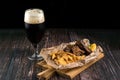 Pork ribs in honey mustard glaze with potatoes served on a wooden board and a glass of dark beer. Food concept of snack and Royalty Free Stock Photo