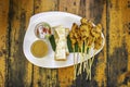Pork Satay with coconut milk and bread with sauce in white plastic plate on wooden table