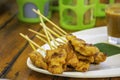 Pork Satay with coconut milk with sauce in white plastic plate on wooden table