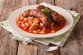 Pork sausages with beans and cooked tomatoes on a plate close-up Royalty Free Stock Photo