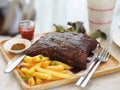 Pork Spareribs BBQ, Barbeque Pork Ribs with french fries vegetable salad, tomato sauce in a clear glass on wooden tray, food Royalty Free Stock Photo