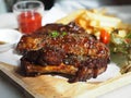 Pork Spareribs BBQ, Barbeque Pork Ribs with french fries vegetable salad, tomato sauce in a clear glass on wooden tray, food Royalty Free Stock Photo