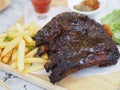 Pork Spareribs BBQ, Barbeque Pork Ribs with french fries vegetable salad, tomato sauce in a clear glass on wooden tray, food Royalty Free Stock Photo