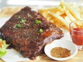 Pork Spareribs BBQ, Barbeque Pork Ribs with french fries vegetable salad, tomato sauce in a clear glass on wooden tray, food Royalty Free Stock Photo