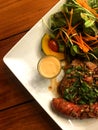 Pork steak and sausage with spicy herbal sauce and salad with dressing in plate pu