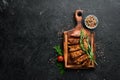 Pork steak with spices on black stone background. Top view. Royalty Free Stock Photo