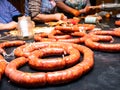 Pork strings on a black table while working women stuff the pork guts with meat to make sausages