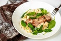 Pork tenderloin medallions on risotto with parmesan and spinach leaf on white plate and towel Royalty Free Stock Photo