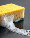 Porous Yellow and Blue Sponge with White Bubbles on Dark Gray Surface in Studio Lighting Royalty Free Stock Photo