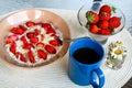 Porridge with strawberry, blue cup of tea, flowers and strawberry on glass bowl